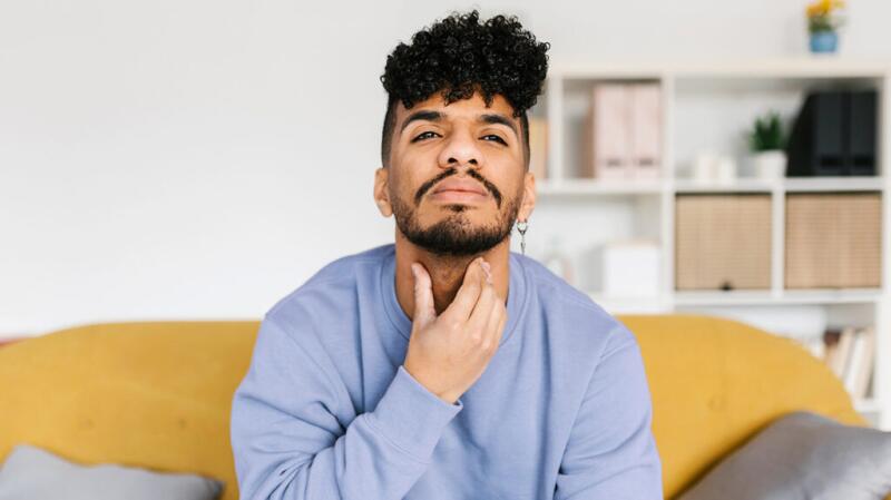 A man touching his throat with his hand