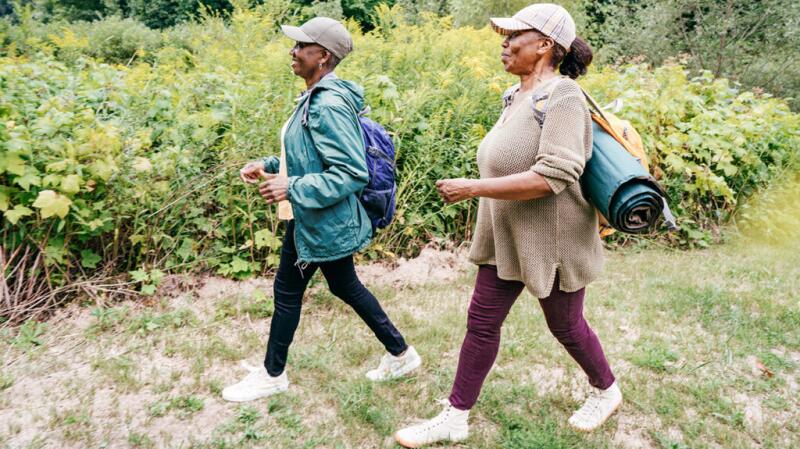 Two people are walking outdoors in a grassy area
