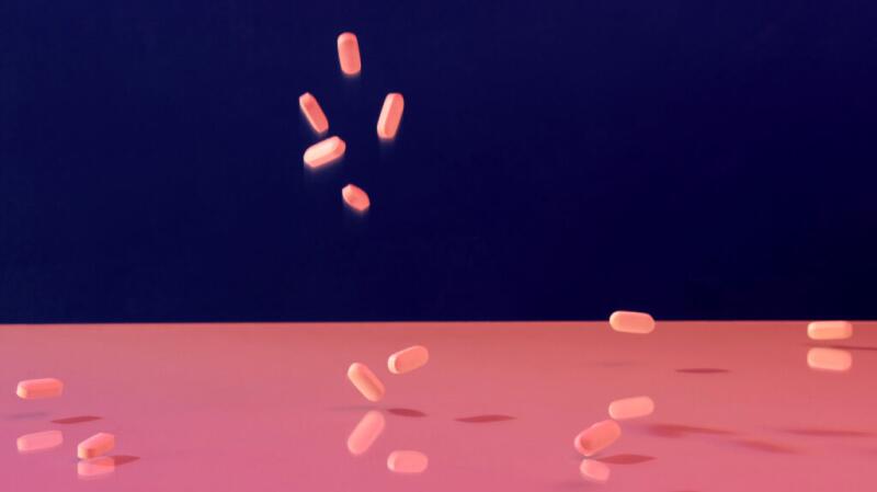 Image of pink pills falling against a blue and pink background