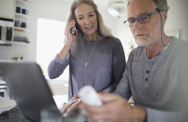 Middle aged Caucasian couple looking at medicine bottle while on phone