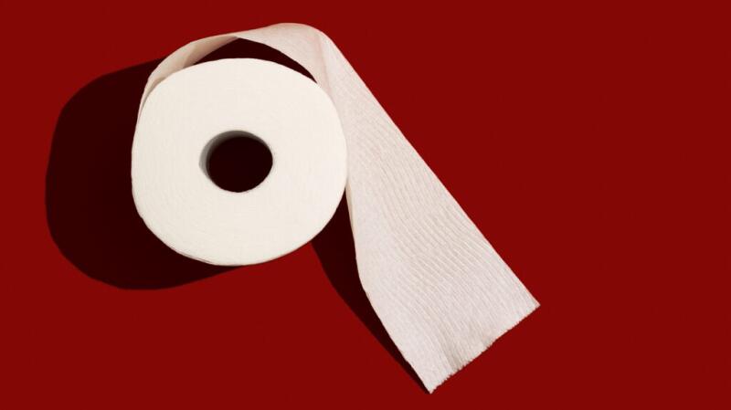A roll of toilet paper set against a red background