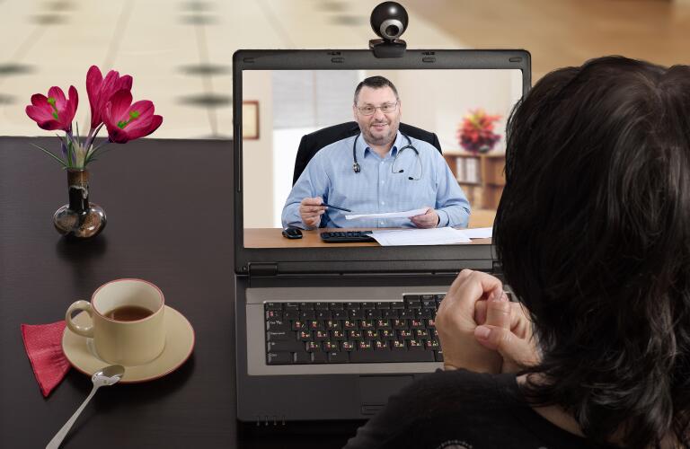 Female patient having telemedicine appointment with male doctor over laptop camera