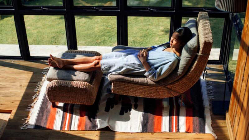 Woman lying on chair on sunroom relaxing