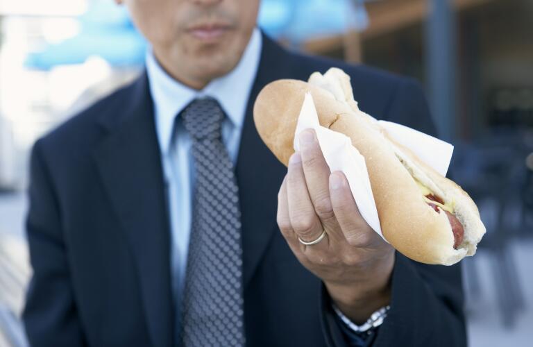 Unseen Caucasian businessman eating hot dog