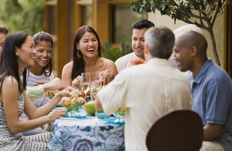 diverse group of young friends eating meal outside at city restaurant