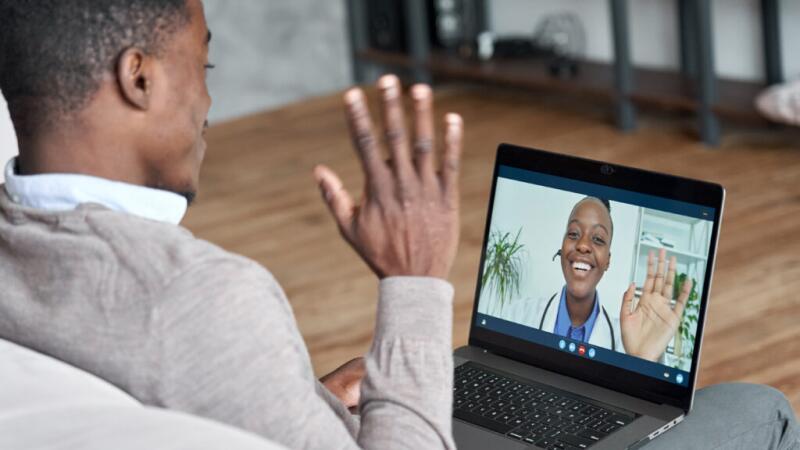 A man talking to his doctor through a video call on his laptop