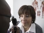 male African American eye doctor examining eyes of middle aged female Caucasian female