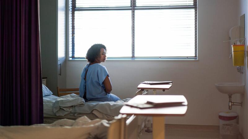 a woman is in hospital sat by a window