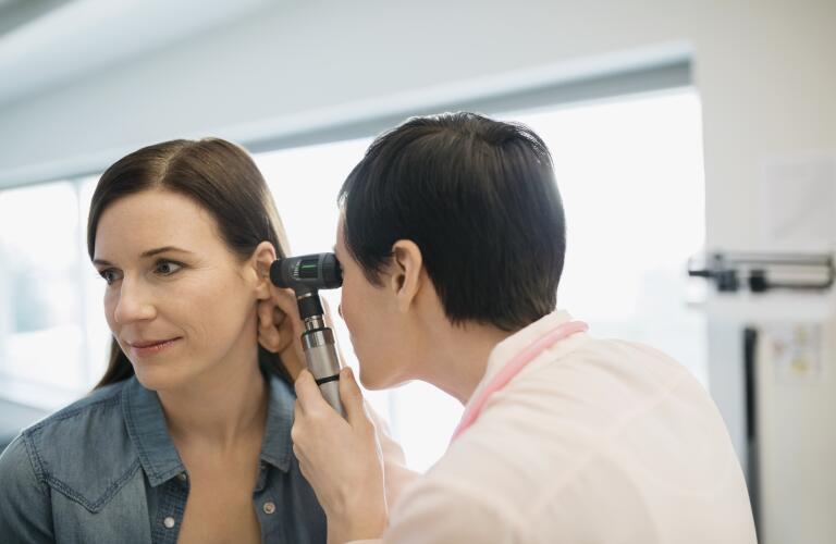 Caucasian woman getting ears examined by female doctor
