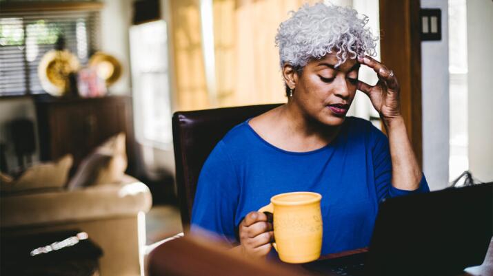 a woman wearing a blue sweater is touching her head
