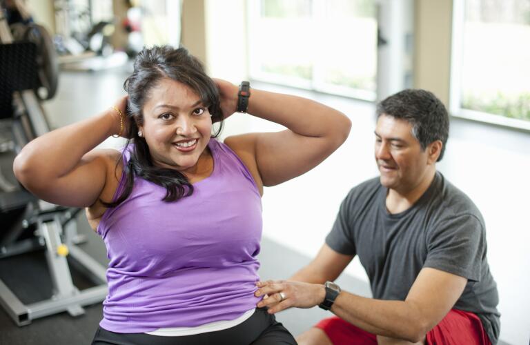 woman-doing-sit-ups-with-trainer