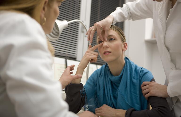 Young Caucasian woman receiving rhinoplasty consultation from doctors