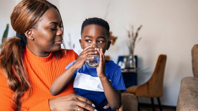 A woman holding her son while he drinks water