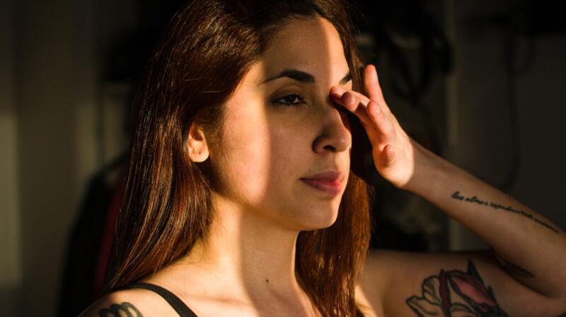A woman rubbing her left eye with her hand