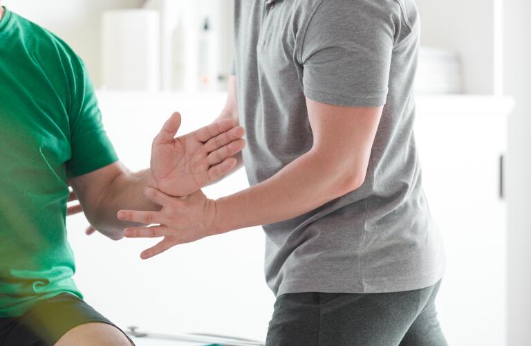 physical therapist examining man's arm movement in rehabilitation center