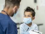 young boy and doctor wearing disposable surgical masks at doctor's appointment