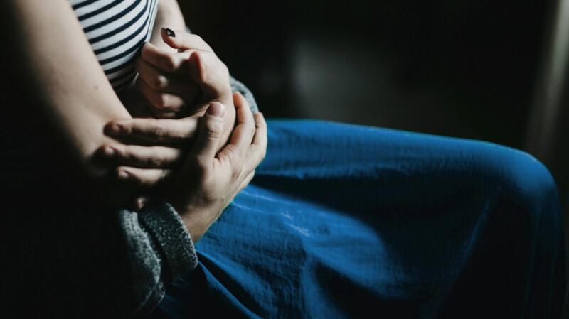 Close-up of woman with hand on belly and man's hand holding hers