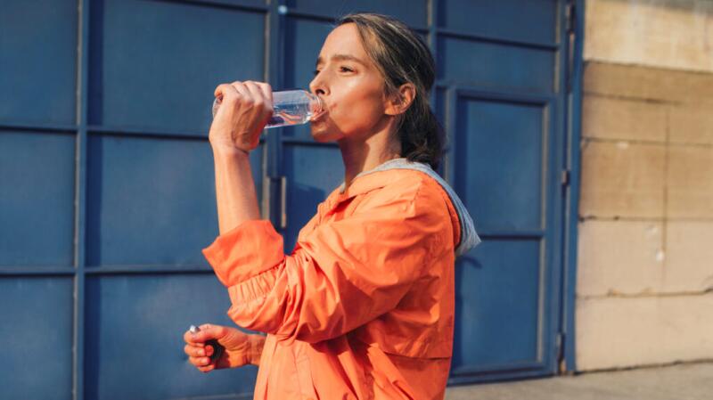 a woman is drinking water outside