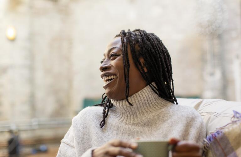 Middle aged African American woman smiling and laughing with cup of coffee