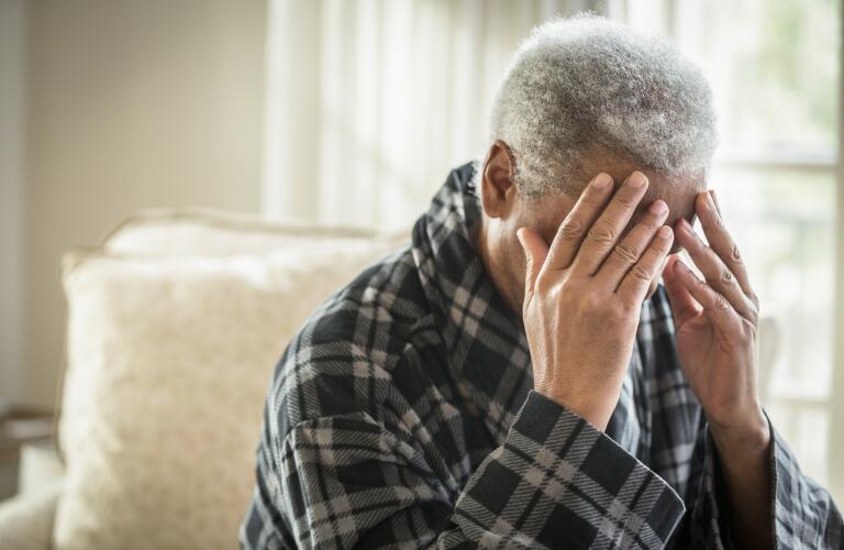 disoriented African American senior male with head in hands