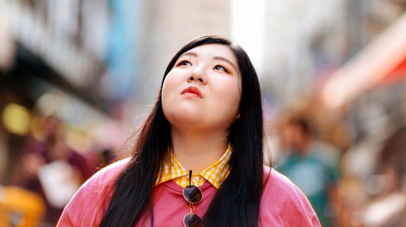 Person walking on busy city street looking up in thought