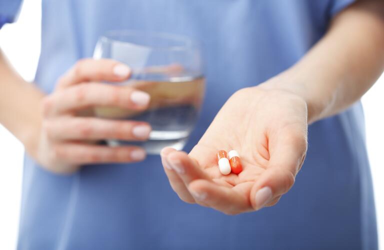 woman-holding-out-pills-and-glass-of-water