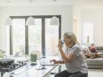 woman sitting at kitchen table in front of laptop using inhaler