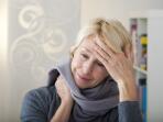 Older woman wearing scarf holding hand on forehead with headache or fever