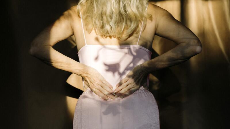 The back of a female with her hands resting on her lower back