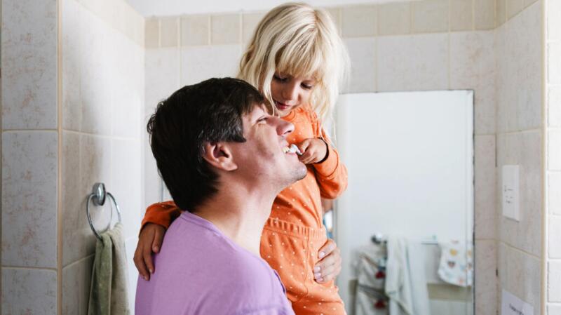 child brushing fathers teeth