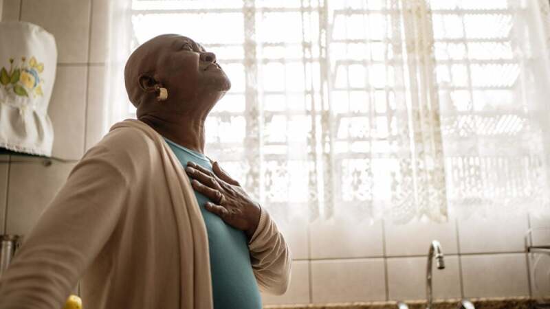 A person is looking up with a hand on their chest.