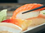 Close-up of chopsticks picking up piece of salmon nigiri sushi