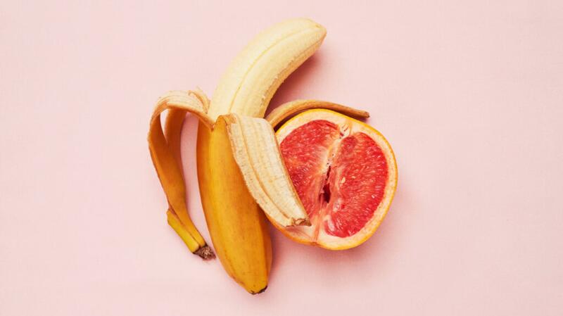 A banana and a grapefruit on a pink background