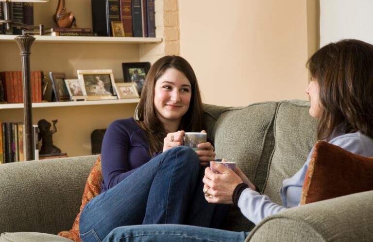 Mom and daughter sitting on couch talking