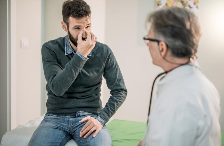 adult male patient describing his nasal problem to a physician