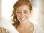 Close-up of young red-headed Caucasian woman with freckles smiling