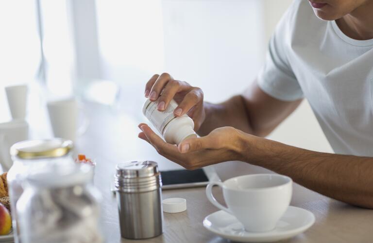 Man taking vitamins or supplements from bottle