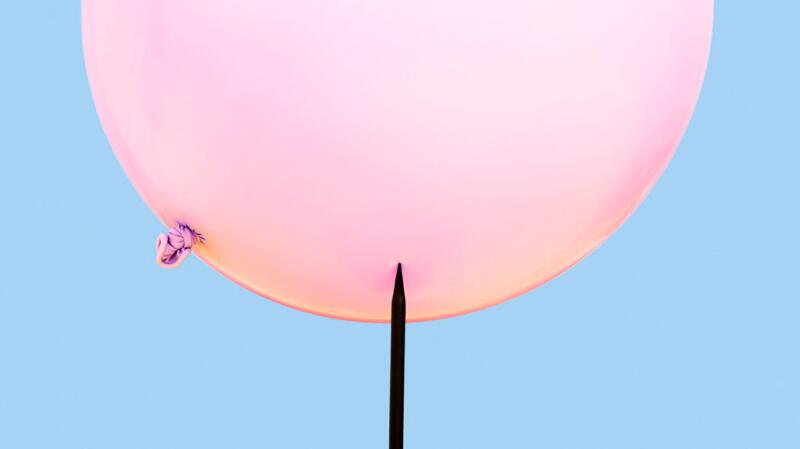 A needle about to pop a balloon