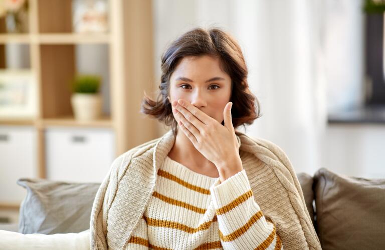 sick woman in blanket coughing at home