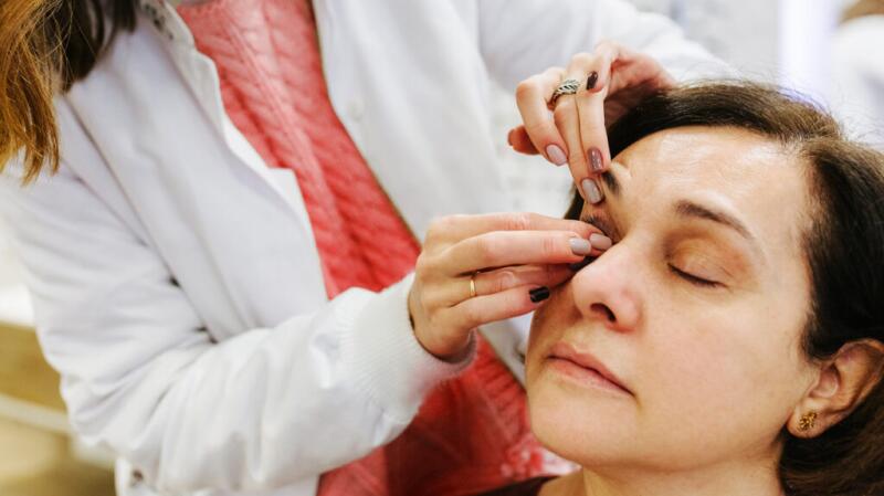 doctor examining a woman's eye and eyelid