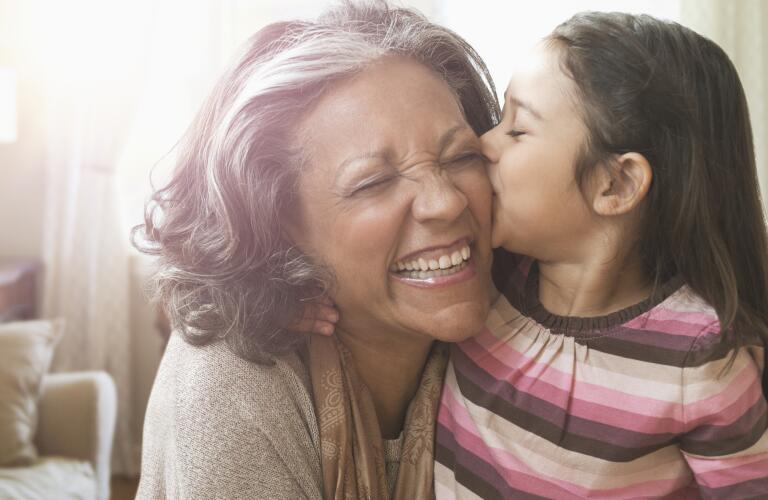 Hispanic granddaughter kissing grandmother on the cheek