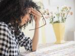 woman sitting at table with headache