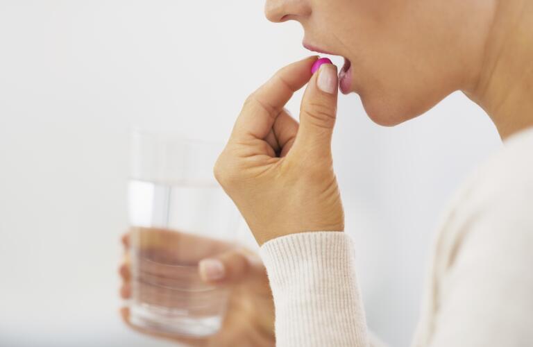 Closeup on young woman eating pill