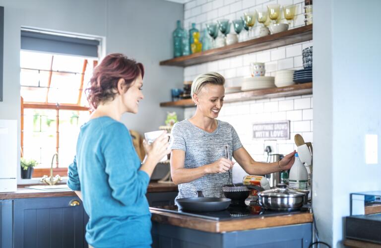Gay female Caucasian couple cooking together in home kitchen