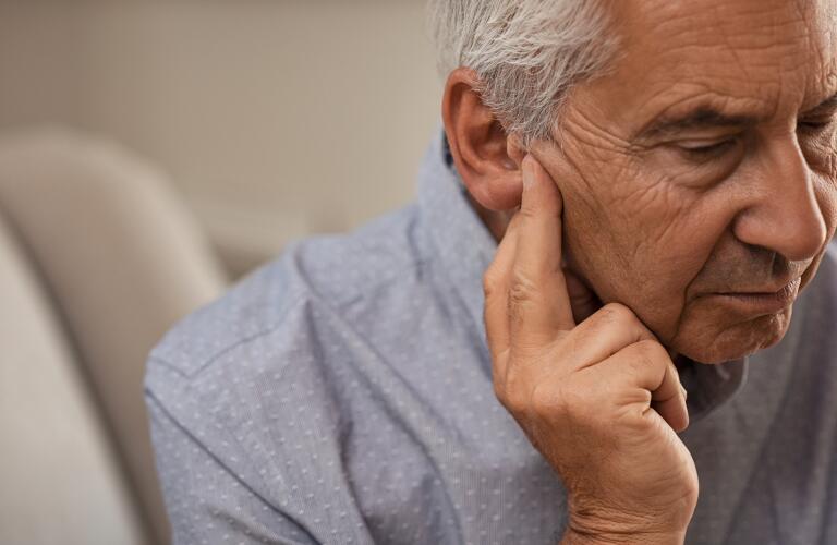 Senior Caucasian man holding fingers to ear