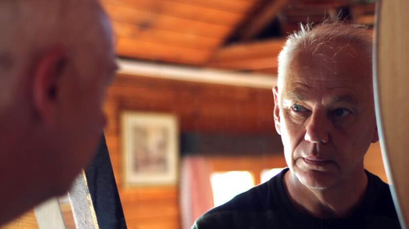 An older man looking at his face in the mirror