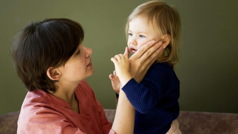mother looking closely at her child with her hand on child's face