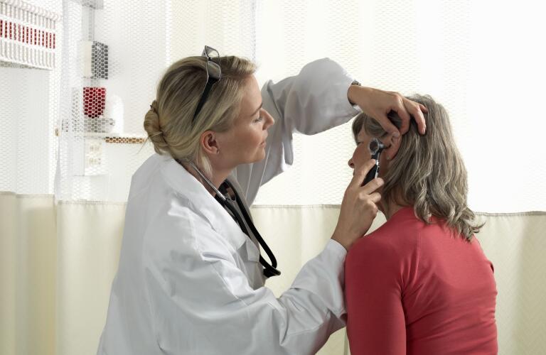 Older Caucasian woman getting ear exam from female Caucasian ear, nose and throat doctor