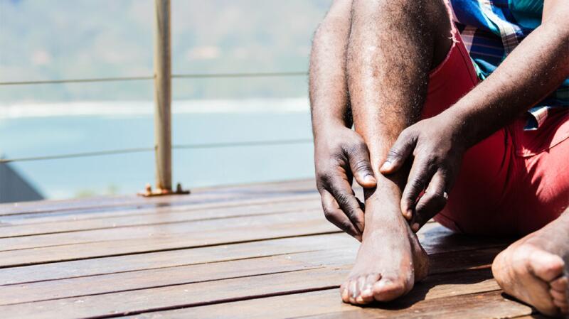 A man is touching his ankle.