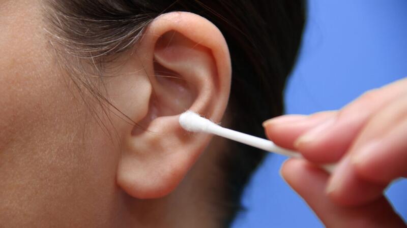 A person using a Q-tip in their ear